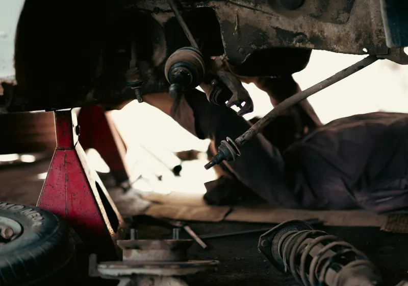Mechanic working on suspension and brakes under a raised vehicle